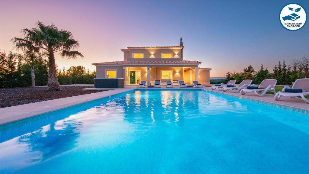 a swimming pool with chairs and a house at Villa Paradise - Moradia tranquila com piscina aquecível e BBQ - Albufeira in Lagoa