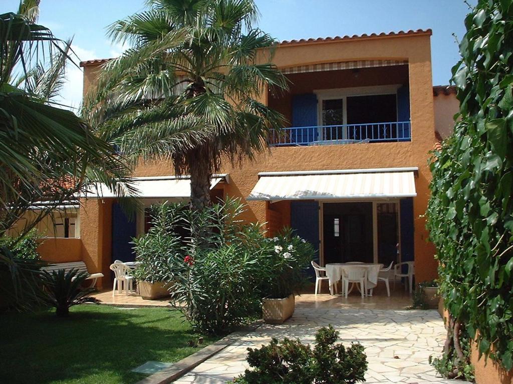 een huis met een palmboom en een patio bij Residence la Catalane in Saint Cyprien Plage