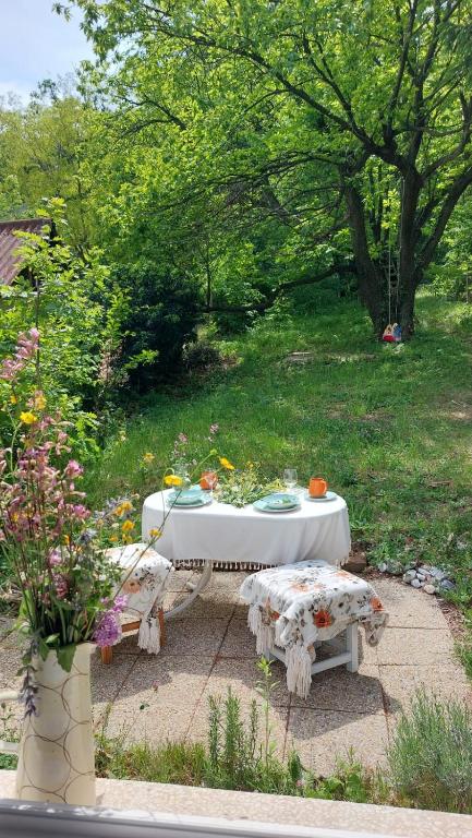a white table and bench in a garden with flowers at Gesztenyés Backpackers in Kőszeg