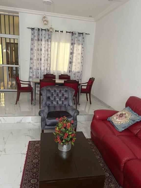 a living room with a red couch and a table at Zahra Résidence in Rufisque