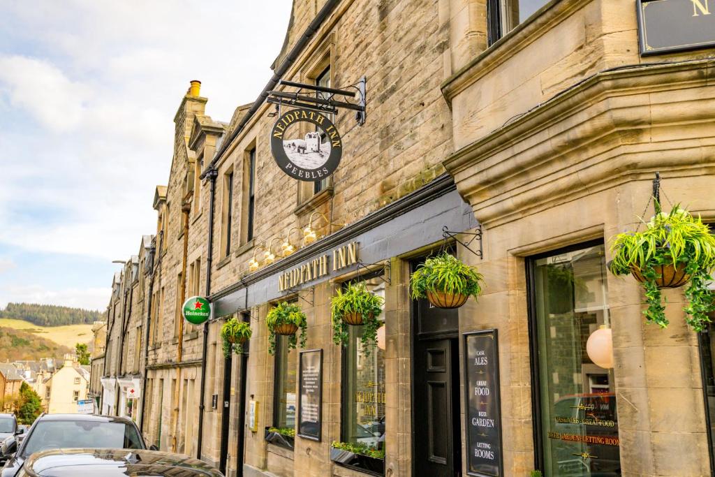 a building with a clock on the side of a street at Neidpath inn in Peebles