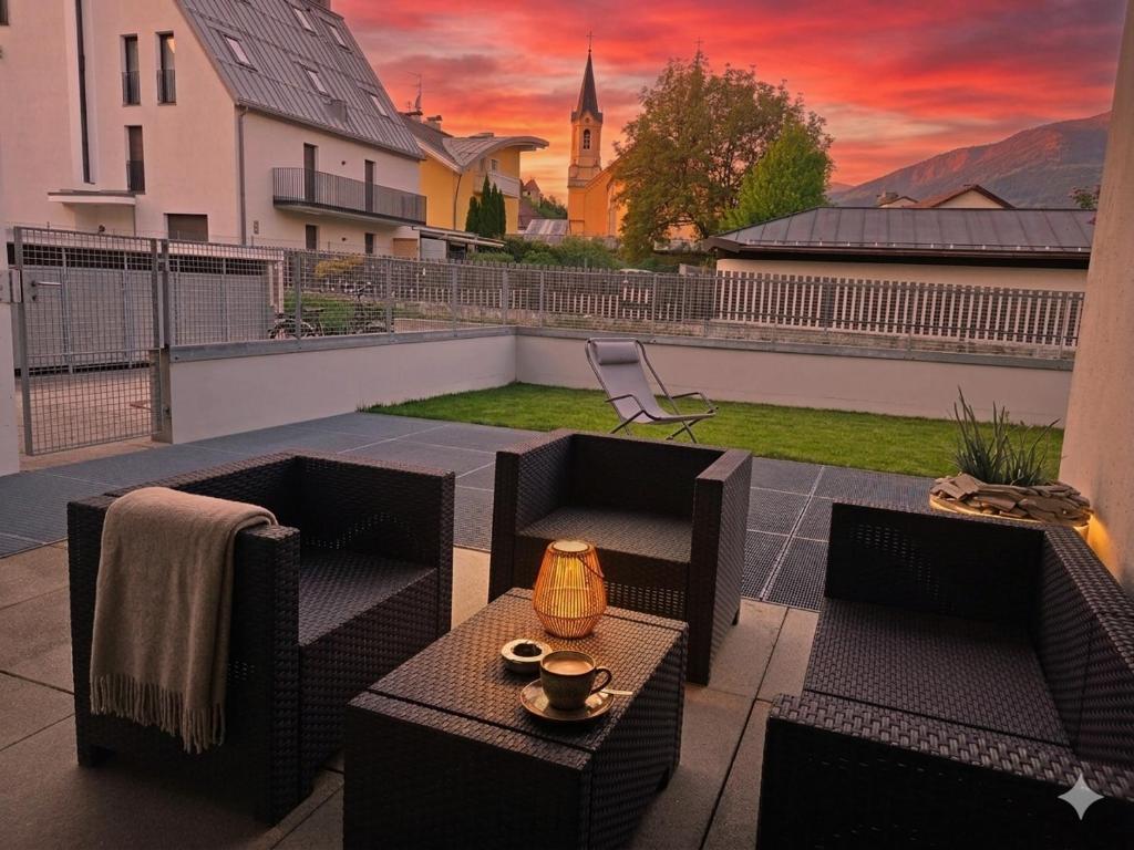 a patio with two chairs and a table with a sunset at Apartment Bruneck Central in Brunico