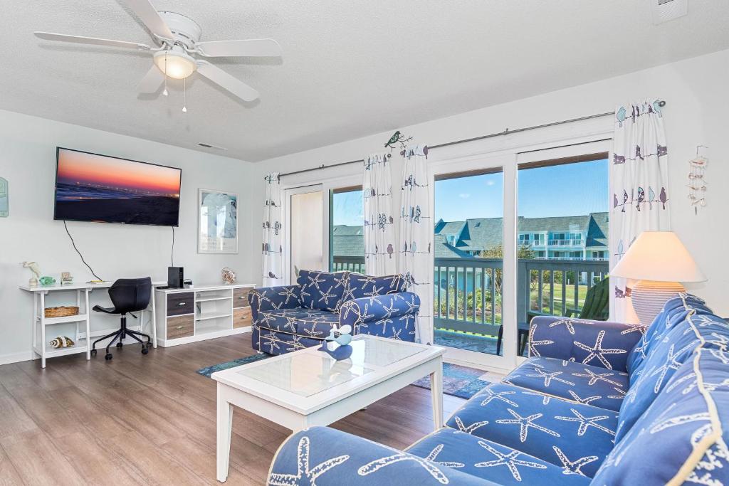 a living room with a blue couch and a table at Pebble Beach I-211 in Emerald Isle