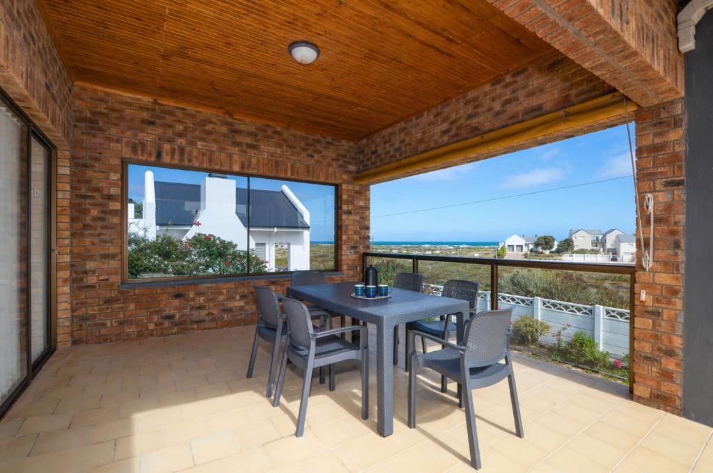 a patio with a table and chairs and the ocean at Cosy House in Yzerfontein