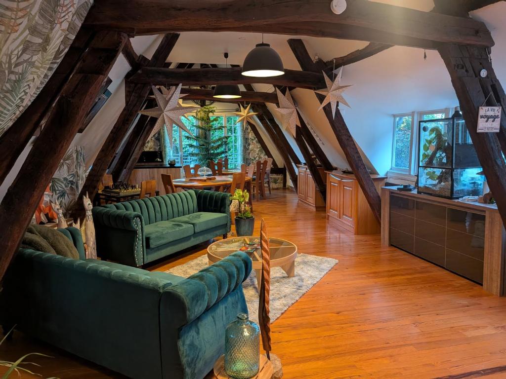 a living room with green couches and a table at Au Bois Dormant B&B in Tillé
