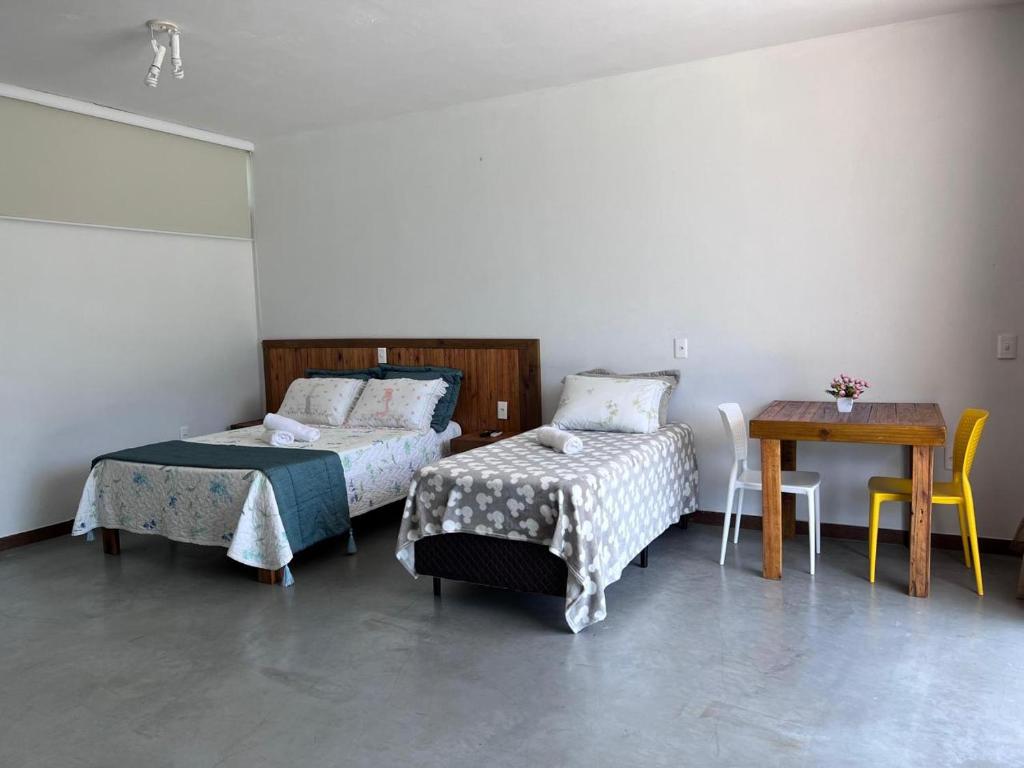 a bedroom with two beds and a table and a table at Vistas de Gravatá in Gravatal
