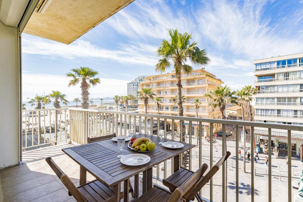 a table with fruit on a balcony with palm trees at Mer Vue Sublime in Canet-en-Roussillon