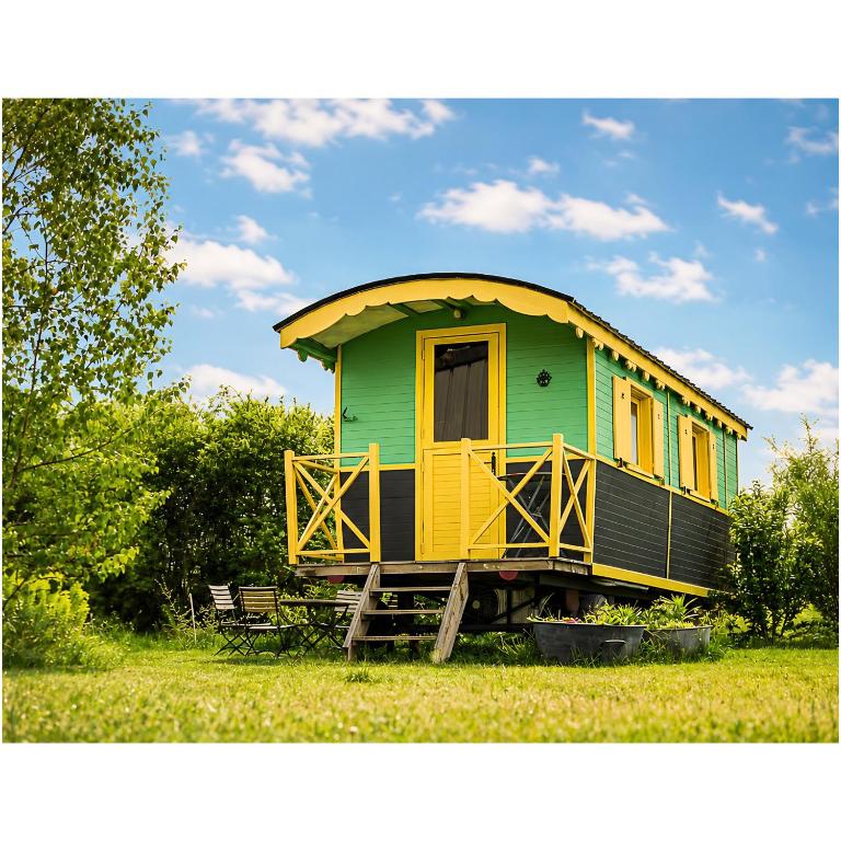 a green and yellow house sitting in the grass at La roulotte MAGIC ! des Grillots in Beaulon