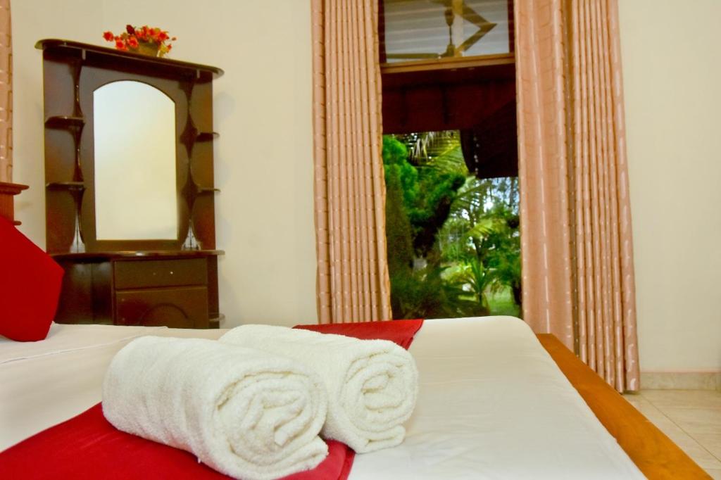 a bed with white towels on it with a mirror at Hamilton View in Negombo