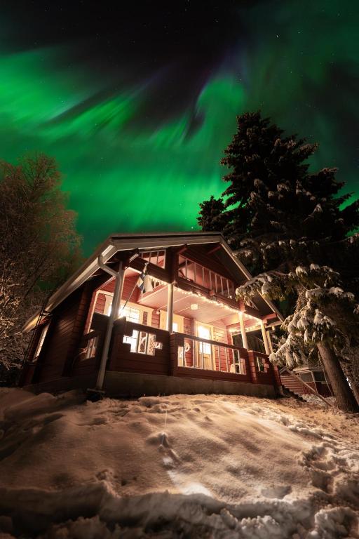 a cabin with the aurora in the sky at Lapland Aurora Riverside in Raiskio