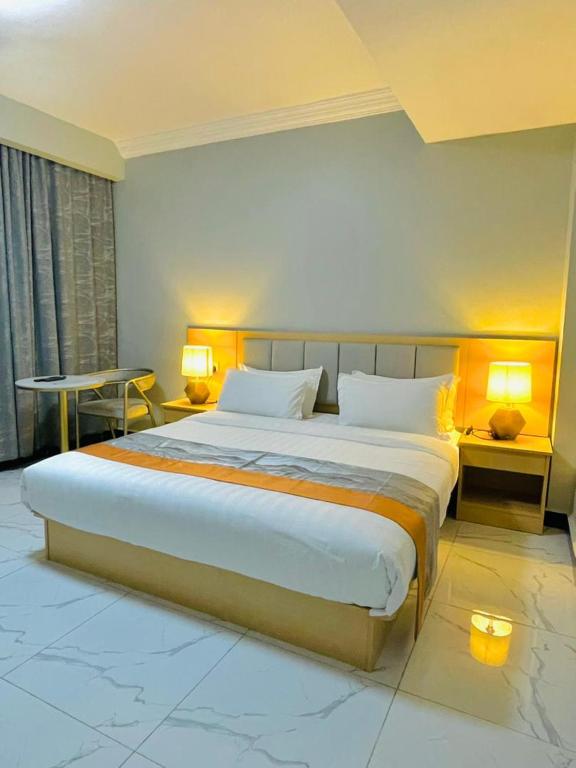 a large bed in a hotel room with two lamps at Abad Hotel in Mogadishu