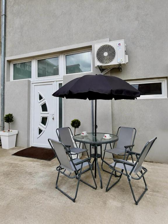 a table with chairs and an umbrella in front of a building at Apartment Belase in Plav