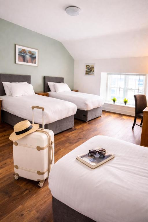 a hotel room with three beds and a suitcase at Henehan's Town House in Westport