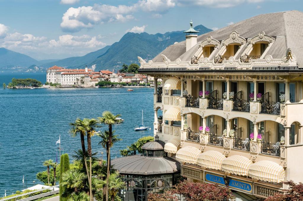 a building with balconies and a body of water at Hotel Villa e Palazzo Aminta in Stresa