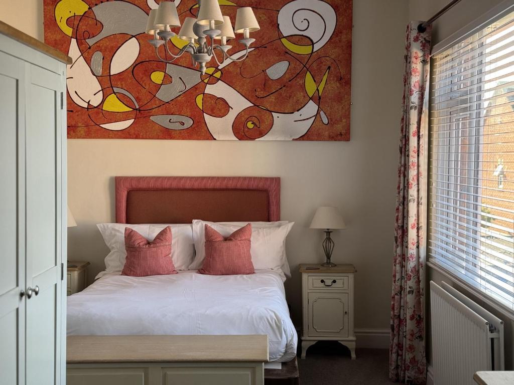 a bedroom with a bed with a painting on the wall at The Old Fourpenny Shop Hotel in Warwick