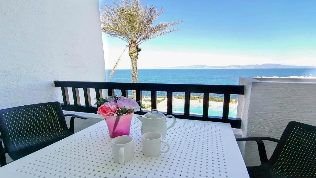 a white table with flowers and a view of the ocean at Apartamento Aqua by VACAY L'Escala in L'Escala