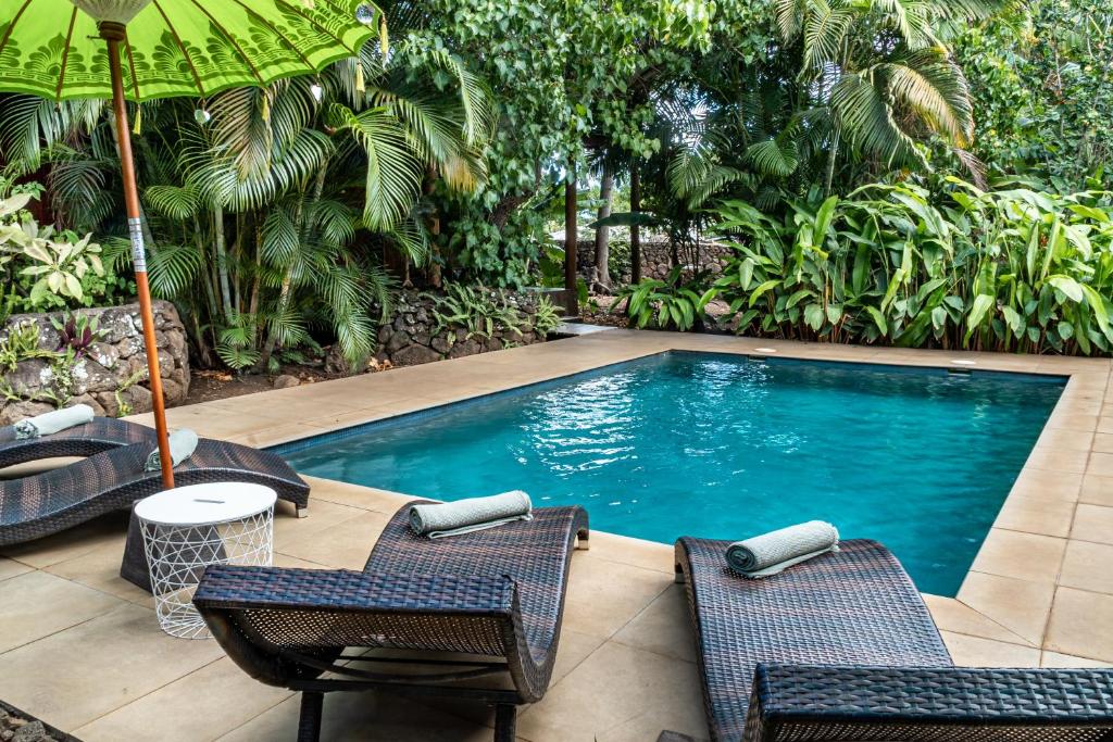 a swimming pool with two chairs and an umbrella at Rapa Nui, La Residence in Hanga Roa