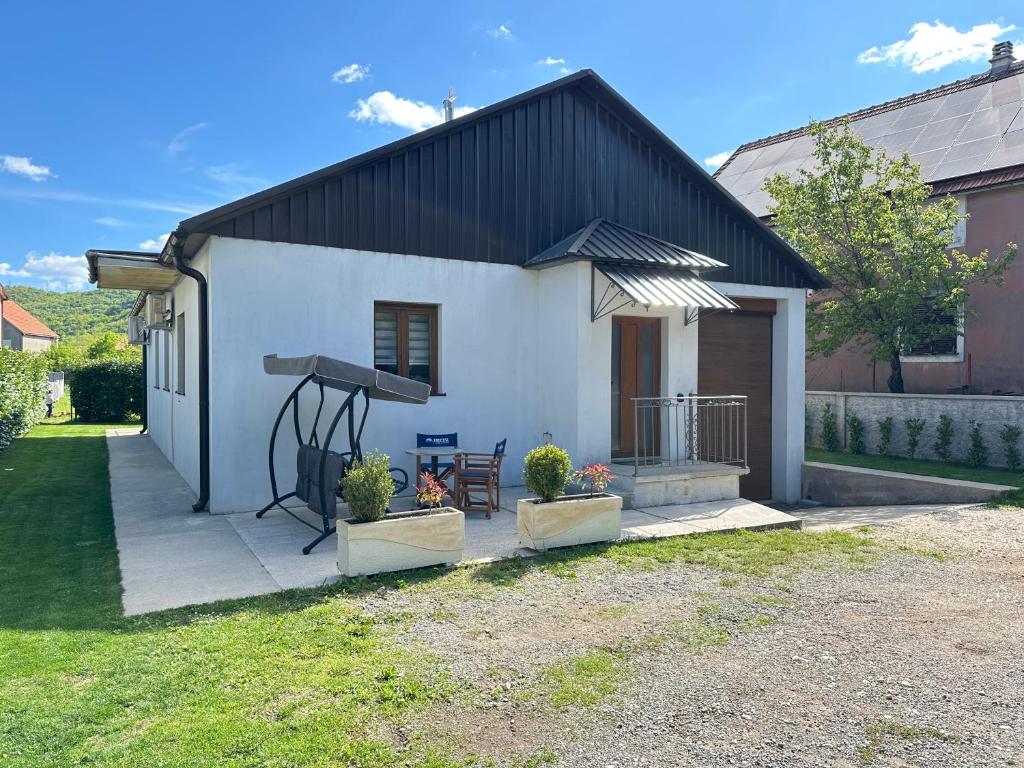 a white house with a black roof and two plants at Apartman T&T in Cetinje