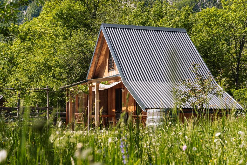 a house with a metal roof in a field of grass at Sweet Bee Cottage in Bovec