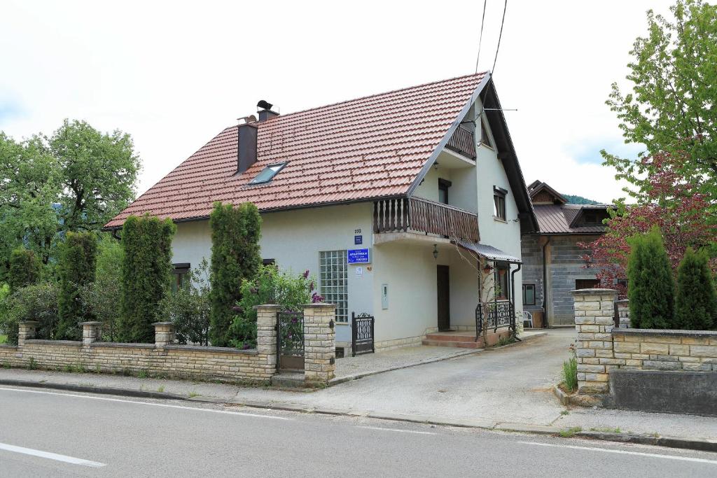 a white house with a brown roof on a street at Guest House Sveti Marko Gacka in Otočac