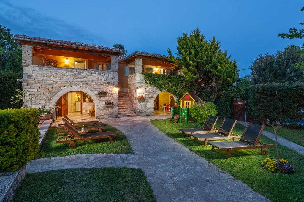 a stone house with benches in the yard at Casa Karnevali in Žminj