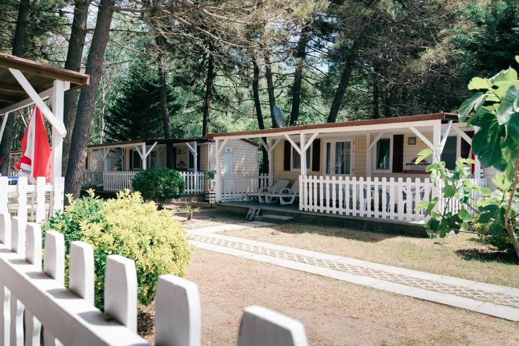a white house with a fence in front of it at Safari Beach & Camping in Donji Štoj