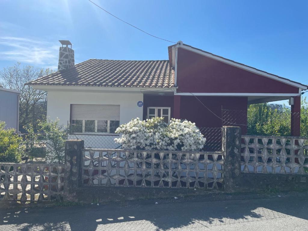 a house with a fence and flowers in front of it at Casita San Simon in Bayón