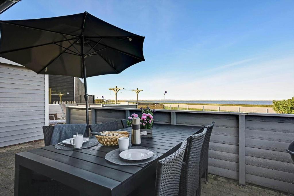 a table with an umbrella on a deck with the beach at C11769-Hemmet-Vester-Faelled-14 in Falen