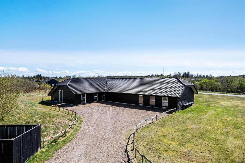 a black house with a gravel driveway at JB500-Brovst-Kronvildtvej-31 in Tranum Strand