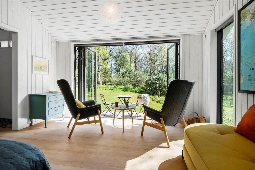 a living room with chairs and a table and a window at 30717-Odder-Alrovej-153 in Amstrup