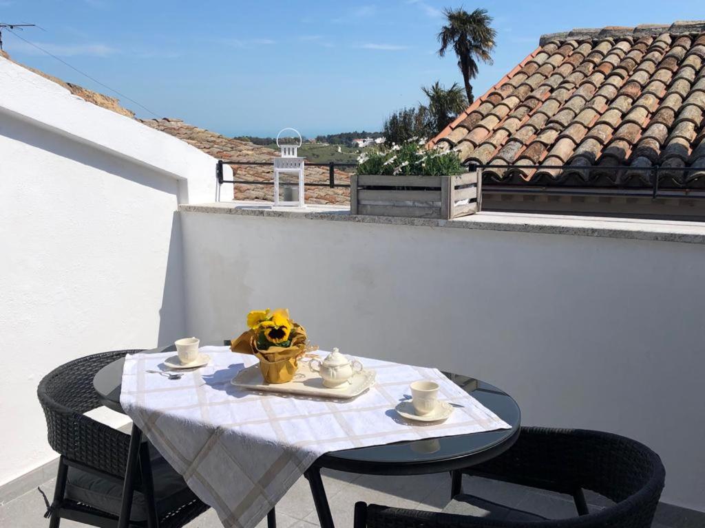 a table with two chairs and a table with two cups and a bowl of flowers at B&B Porta Girone in Civitanova Alta