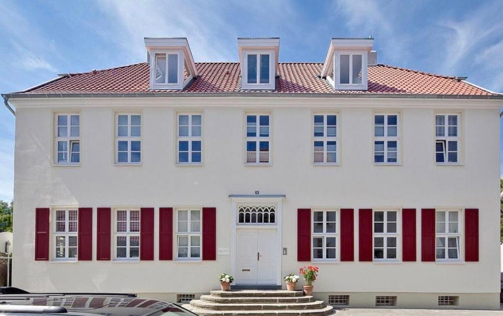 a large white house with red shutters at Schonekind Appartement Soest in Soest