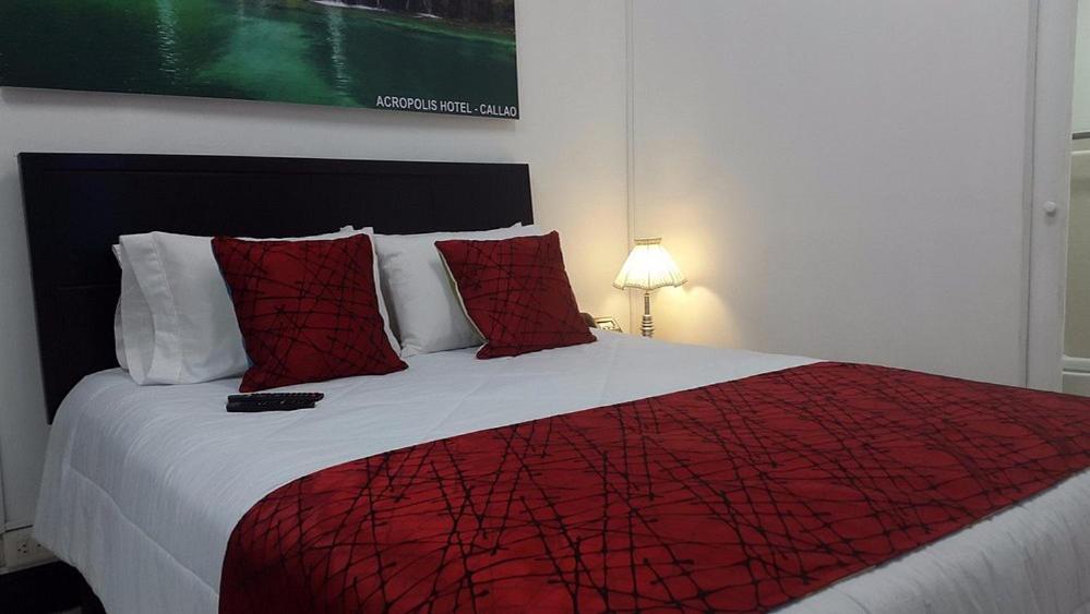 a bedroom with a large bed with a red blanket at Hotel Acropolis Callao in Lima