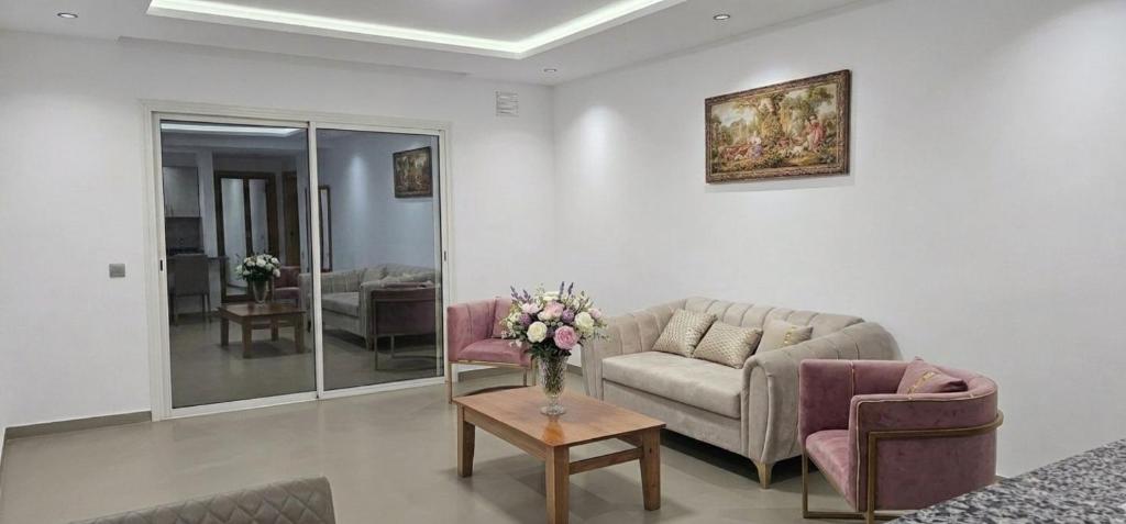 a living room with a couch and a table with flowers at Apartment in recent residence in Monastir