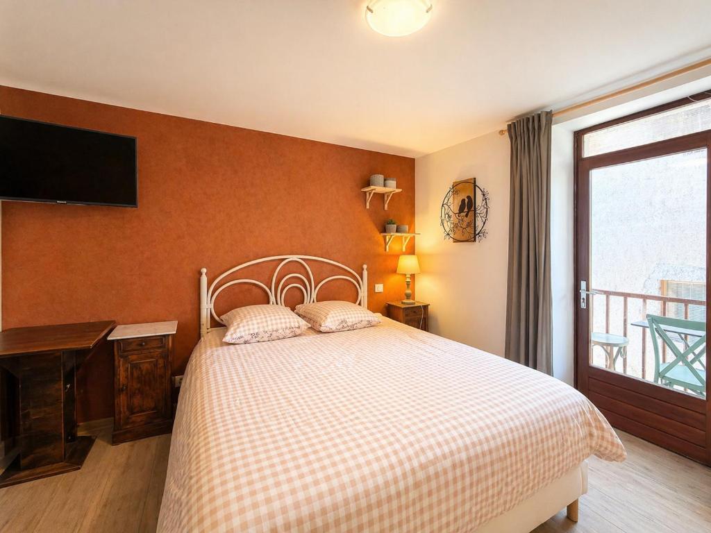 a bedroom with a bed and a tv on the wall at Le Doux Nid in Chanaz