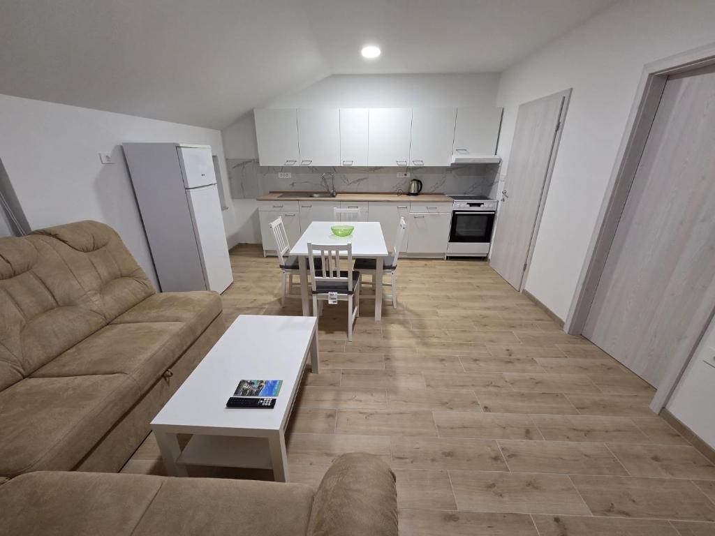 a living room with a couch and tables and a kitchen at Apartma Pri Stevotu in Deskle