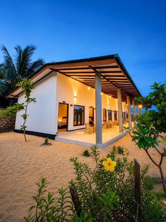 a white building with tables and chairs in a yard at Jesoloresort Arugambay in Arugam Bay