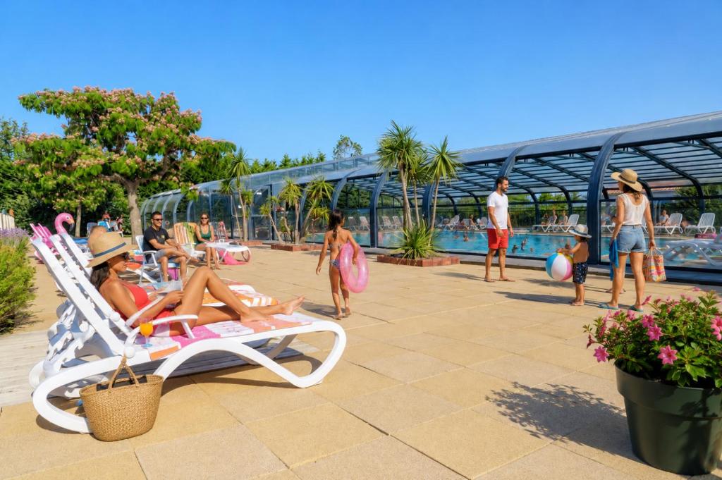 a group of people sitting in a chair near a pool at Camping Cabestan in Bretignolles-sur-Mer