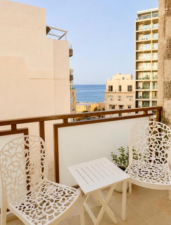 two chairs and a table on a balcony with the ocean at Seaview luxury flat 4 bedrooms in Sliema