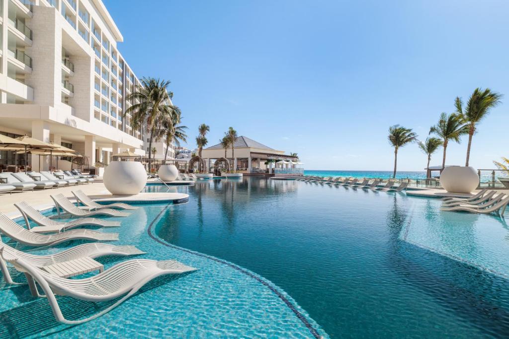 a pool at a resort with lounge chairs and the ocean at Hyatt Zilara Cancun - All Inclusive - Adults Only in Cancún