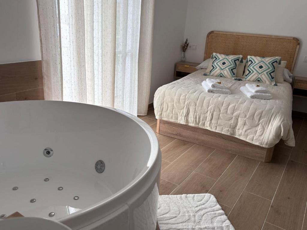 a bathroom with a bath tub next to a bed at Loft Jacuzzi Algarrobo in Arcos de la Frontera