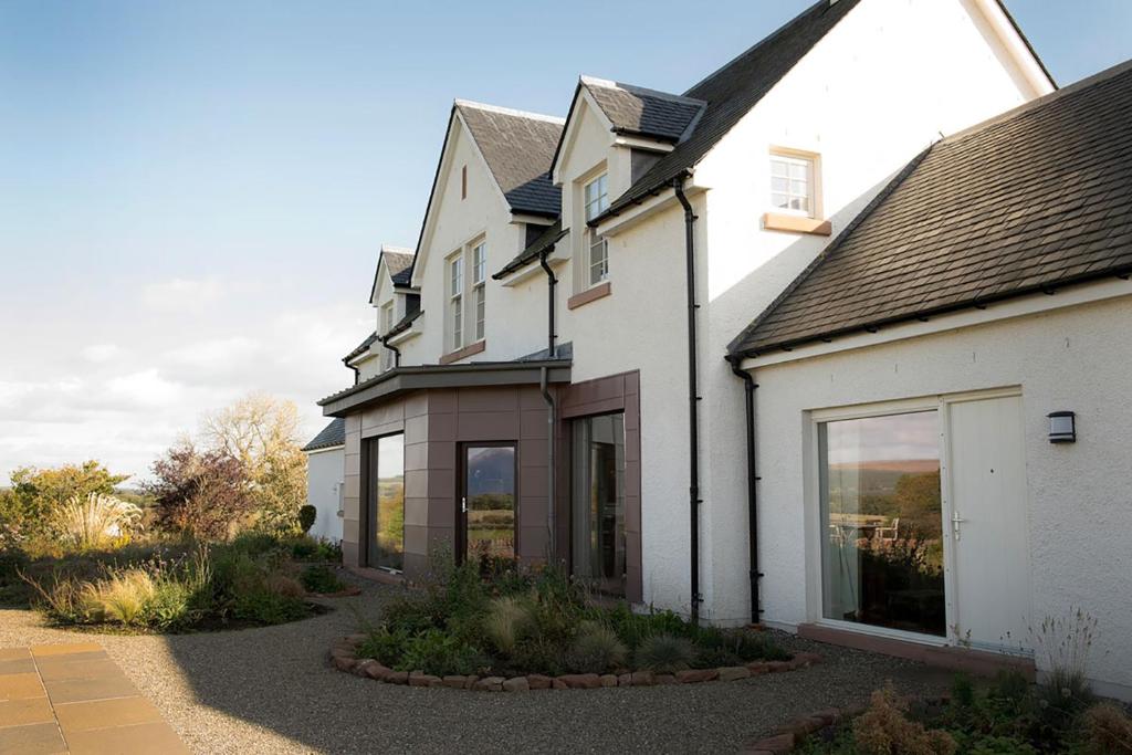 a white house with glass windows and a driveway at Farmhouse with Loch Views in Gartocharn