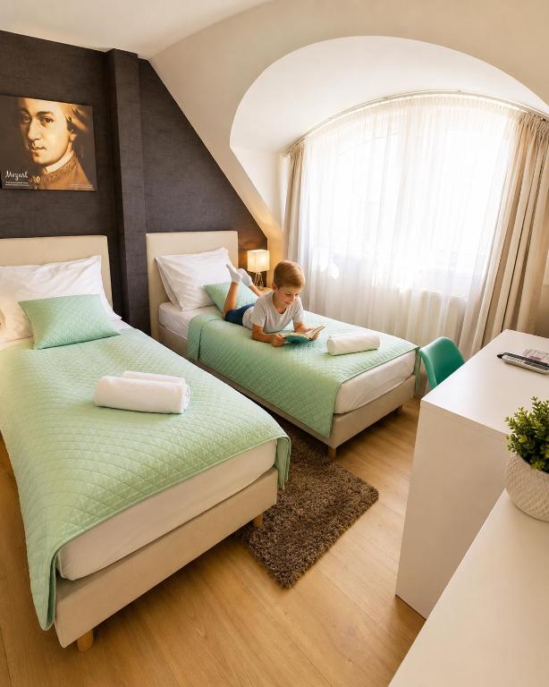 a young boy sitting on two beds in a room at Hévíz Springs - Kehidakustány in Kehidakustány