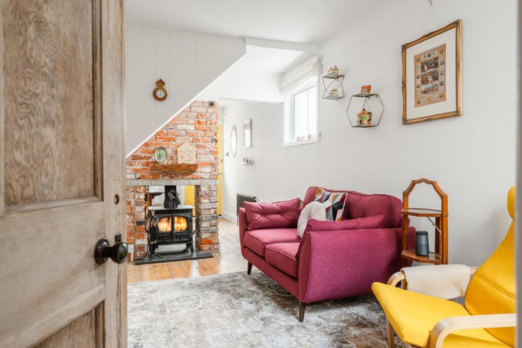 a living room with a pink couch and a fireplace at Twin Tides in Hythe