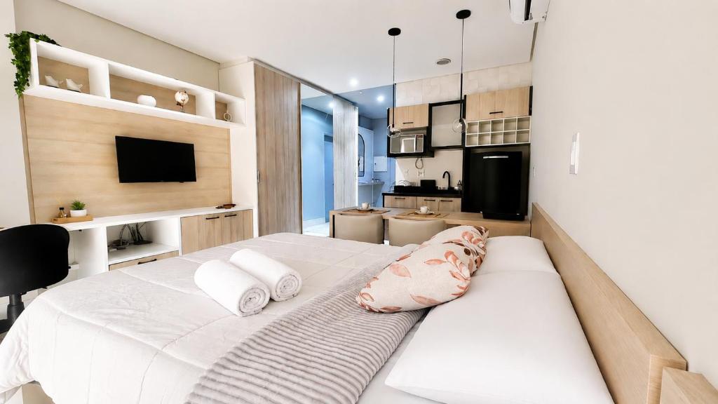 a bedroom with a large white bed and a kitchen at 809 - Studio Moderno no Centro-Batel in Curitiba