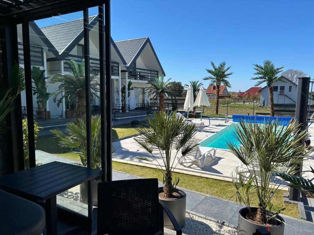 a patio with a table and palm trees and a pool at Sunny Baltic in Jarosławiec