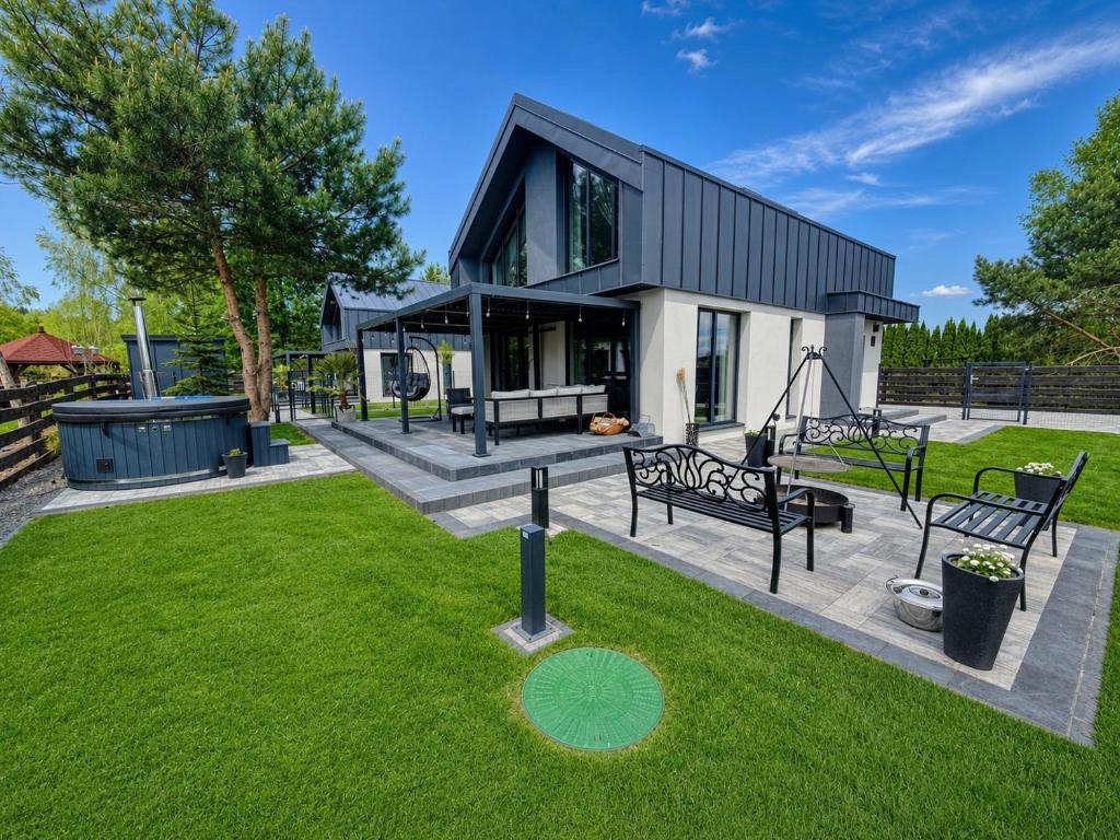 a house with a garden with benches in the grass at Oaza Radęcin in Woldenberg Neumark