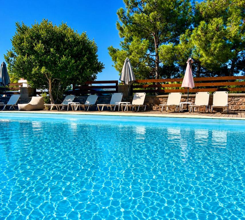 a swimming pool with chairs and umbrellas at PETRINO Hotel in Mythimna