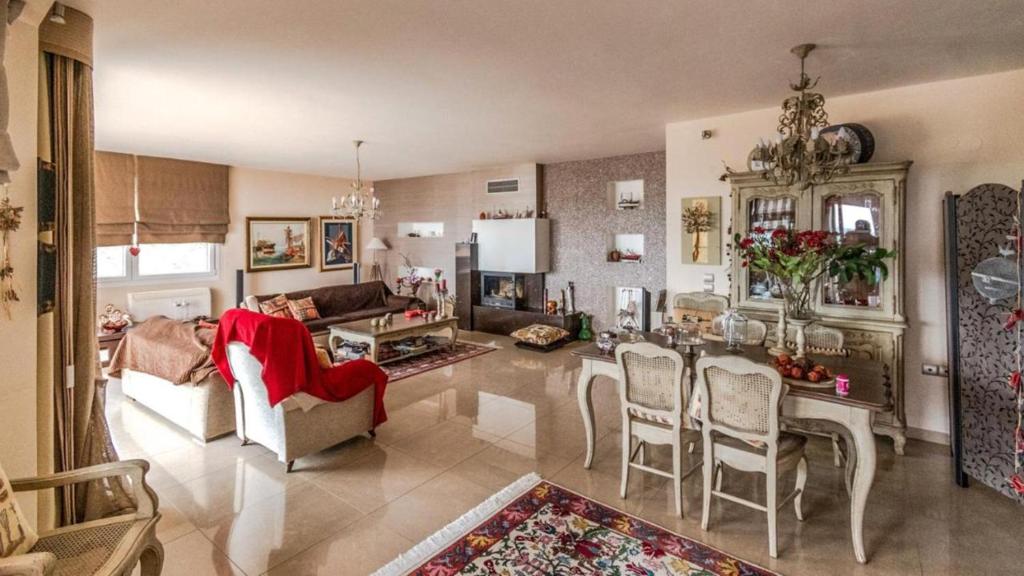 a living room with a couch and a table and chairs at Villa Neraida - Panoramic Lake View Retreat in Neráïdha