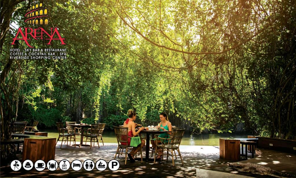 Arena Hotel في بيرووالا: يجلس شخصان على طاولة تحت شجرة